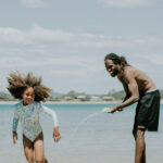 Dad and daughter playing on the beach and having fun on a family holiday.