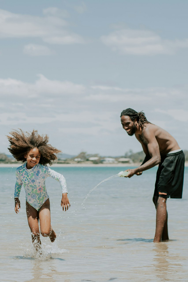 Dad and daughter playing on the beach and having fun on a family holiday.