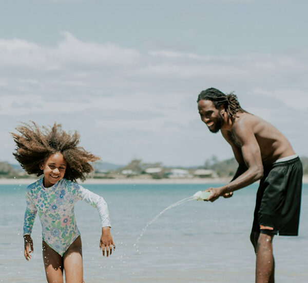 Dad and daughter playing on the beach and having fun on a family holiday.